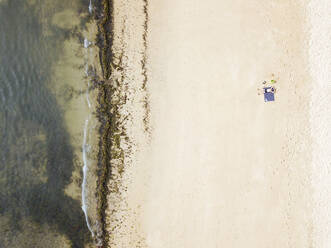 Indonesien, Bali, Luftaufnahme eines Mannes beim Sonnenbaden am Sandstrand von Nusa Dua - KNTF04037