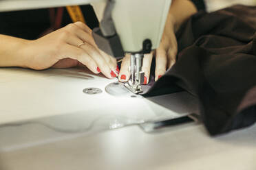 Young fashion designer using sewing machine, close-up - MTBF00273