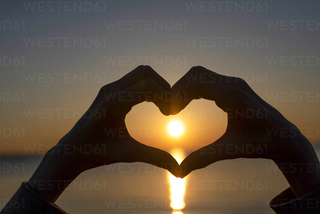 Deutschland, Mecklenburg-Vorpommern, Insel Poel, Silhouette von Händen, die  bei Sonnenuntergang auf dem Meer ein Herz formen, lizenzfreies Stockfoto