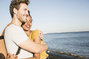 Happy young couple hugging at the waterfront, Lisbon, Portugal - UUF19863