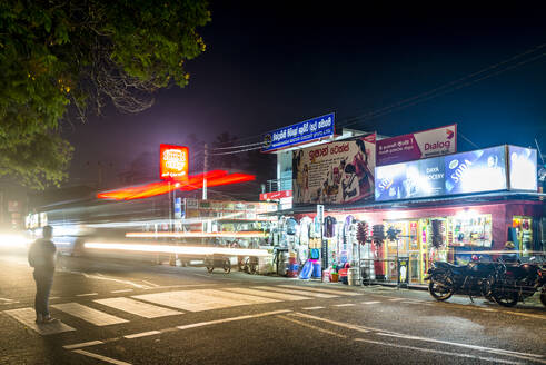 Sri Lanka, Südprovinz, Tissamaharama, Verkehr und beleuchtete Geschäfte bei Nacht - EGBF00516