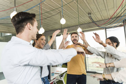 Happy young business people raising their arms in office stock photo