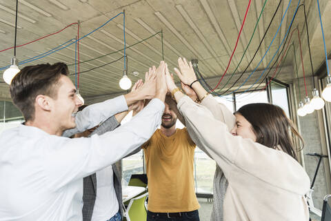 Happy young business people raising their arms in office stock photo