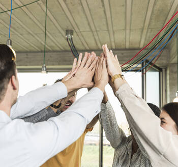 Happy young business people raising their arms in office - UUF19907