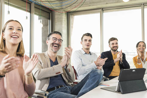 Happy business people applauding during a meeting in boardroom - UUF19918