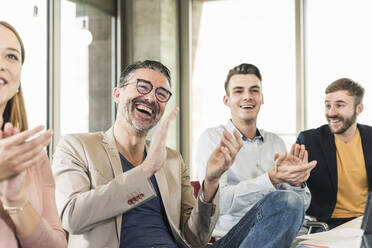 Happy business people applauding during a meeting in boardroom - UUF19919