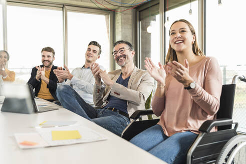 Happy business people applauding during a meeting in boardroom - UUF19920