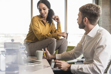 Businessman and businesswoman having a meeting in office - UUF19972