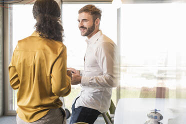 Businessman and businesswoman having a meeting in office - UUF19973