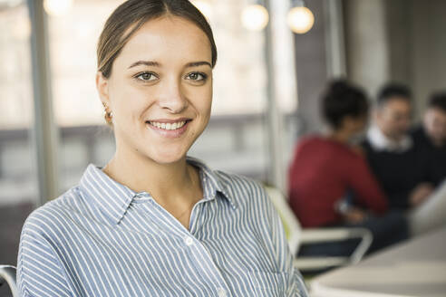 Portrait of smiling young businesswoman during a meeting in office - UUF20013