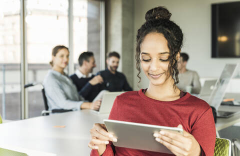 Smiling young businesswoman using tablet during a meeting in office stock photo