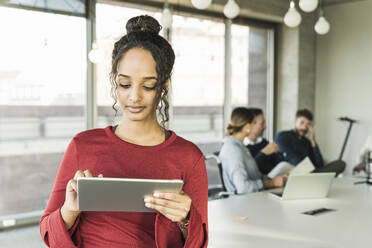 Junge Geschäftsfrau verwendet Tablet während einer Sitzung im Büro - UUF20020