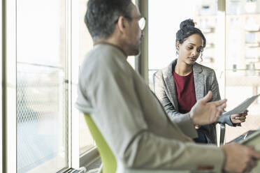 Mature businessman talking to young businesswoman in office - UUF20033