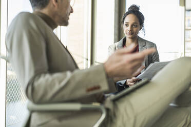 Mature businessman talking to young businesswoman in office - UUF20034