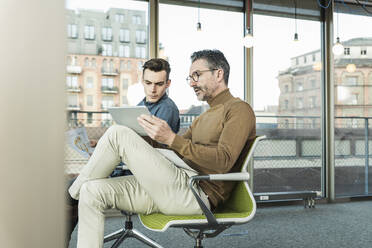 Reifer Geschäftsmann mit Tablet und junger Mann arbeitet im Büro - UUF20055