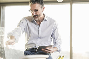 Reifer Geschäftsmann mit Tablet bei der Arbeit im Büro - UUF20062