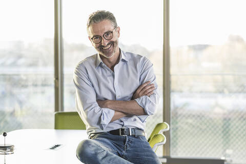 Porträt eines glücklichen reifen Geschäftsmannes im Büro, lizenzfreies Stockfoto