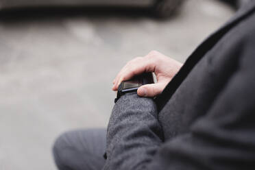 Crop view of businessman checking smartwatch - FMOF00853