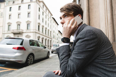 Young businessman with smartwatch on the phone in the city - FMOF00855