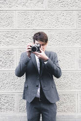 Porträt eines jungen Geschäftsmannes, der ein Foto mit einer Kamera macht - FMOF00861