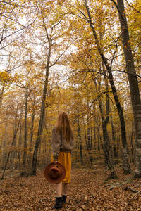Rückenansicht einer modischen rothaarigen jungen Frau im herbstlichen Wald - AFVF04888