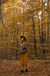 Fashionable redheaded young woman exploring autumnal forest - AFVF04890