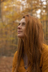 Portrait of redheaded young woman in autumnal forest - AFVF04894