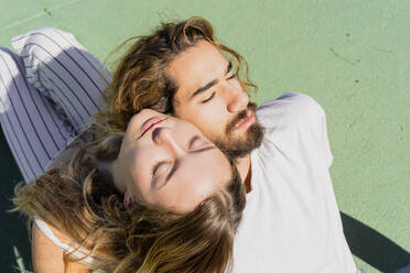 Junges Paar mit geschlossenen Augen entspannt Kopf an Kopf im Sonnenlicht - AFVF04908