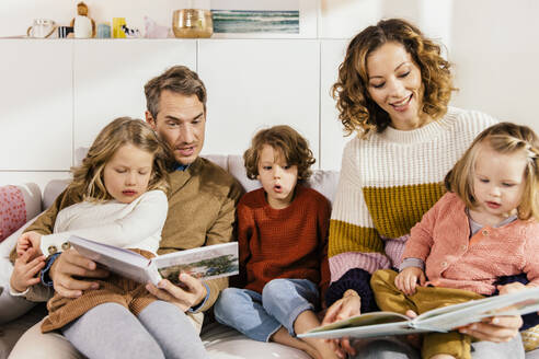 Familie liest Buch mit Töchtern auf der Couch - MFF04967