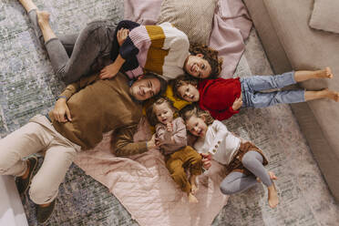 Happy family with three daughters lying on blankets at home - MFF04989
