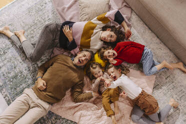 Glückliche Familie mit drei Töchtern, die zu Hause auf Decken liegen - MFF04990