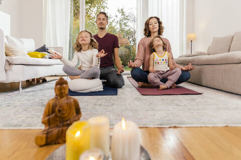 Family meditating together at home stock photo