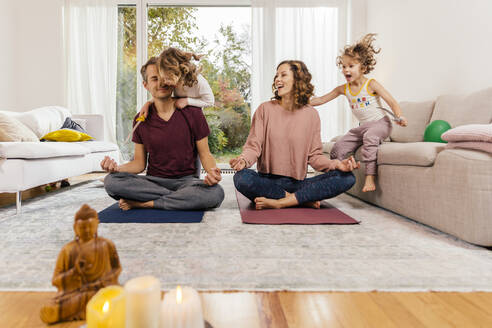 Exuberant girls with parents meditating at home - MFF05020