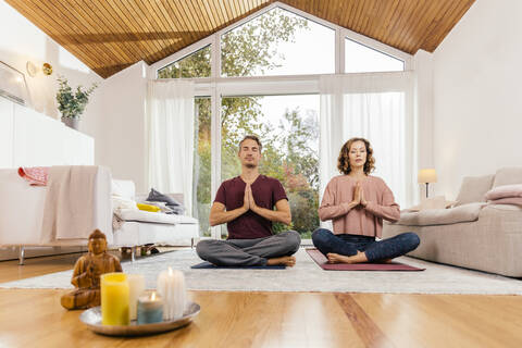 Couple meditating together at home stock photo