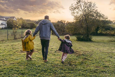 Father with daughters walking on a meadow in autumn - MFF05025