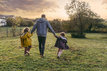 Vater mit Töchtern beim Spaziergang auf einer Herbstwiese - MFF05025