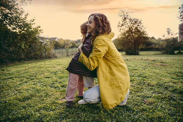 Happy mother and daughter hugging on a meadow in autumn - MFF05028