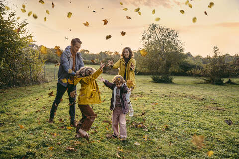 Happy family playing with autumn leaves on a meadow stock photo