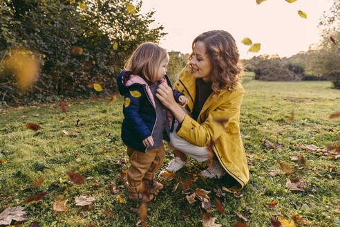 Lächelnde Mutter mit Tochter auf einer Wiese im Herbst - MFF05033
