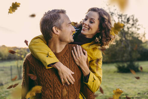 Man giving woman a piggyback ride outdoors in autumn - MFF05037