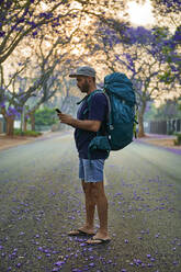 Rucksacktourist mit Smartphone auf einer Straße, Pretoria, Südafrika - VEGF01264