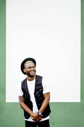 Laughing man in front of a green and white wall - OCMF00980