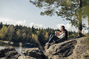 Affectionate couple sitting at the lakeside, Forstsee, Carinthia, Austria - DAWF01070