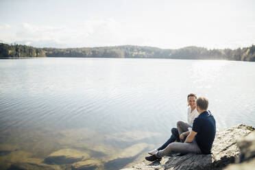 Happy couple sitting at the lakeside, Forstsee, Carinthia, Austria - DAWF01077