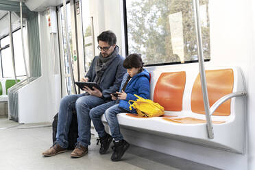 Vater und Tochter in der U-Bahn und mit Tablet und Smartphone - ERRF02514