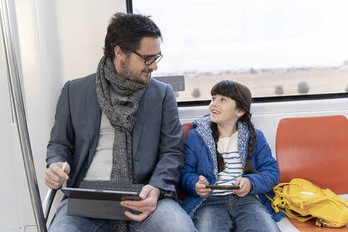 Vater und Tochter in der U-Bahn und mit Tablet und Smartphone - ERRF02515