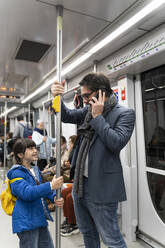 Vater und Tochter in der U-Bahn, Mann mit Smartphone - ERRF02517