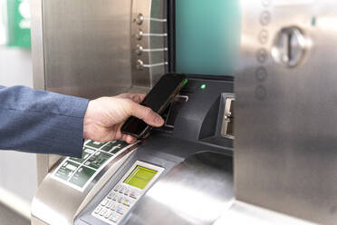 Mann hält Smartphone an Fahrkartenautomat und bezahlt - ERRF02522