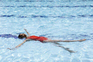 Young woman floating on water in swimming pool - SODF00464