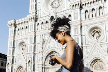 Lächelnde junge Frau, die vor der Kathedrale in ihre Kamera schaut, Florenz, Italien - SODF00491